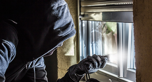 Ein Einbrecher versucht eine Rolllade hoch zu hebeln